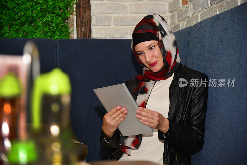 A young Muslim woman works online in a café.